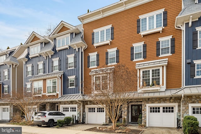 townhome / multi-family property featuring board and batten siding, a standing seam roof, metal roof, a garage, and stone siding