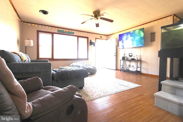 living area with ceiling fan, wood finished floors, visible vents, and baseboards