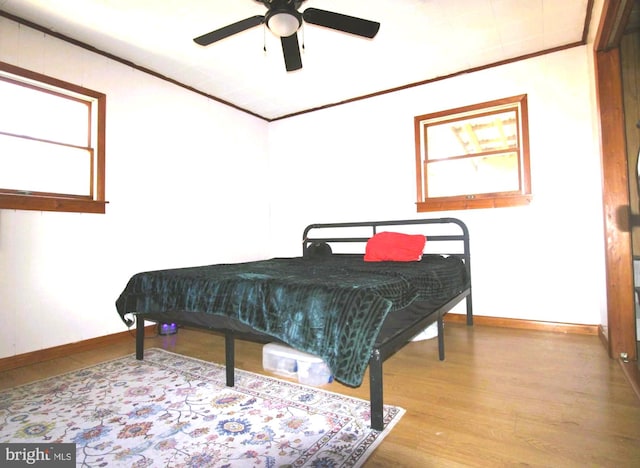 bedroom featuring a ceiling fan, baseboards, ornamental molding, and wood finished floors