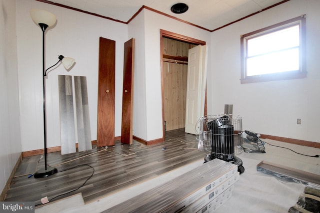 exercise area featuring baseboards, ornamental molding, and wood finished floors