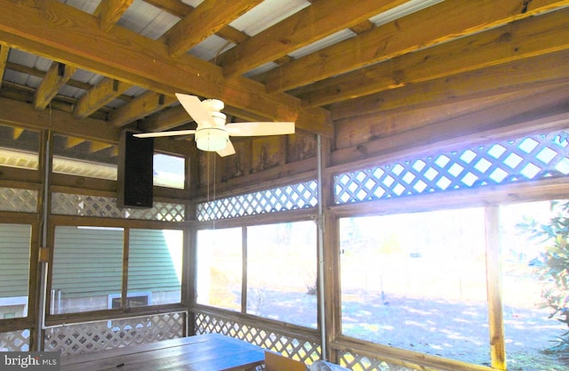 unfurnished sunroom featuring beam ceiling and a ceiling fan