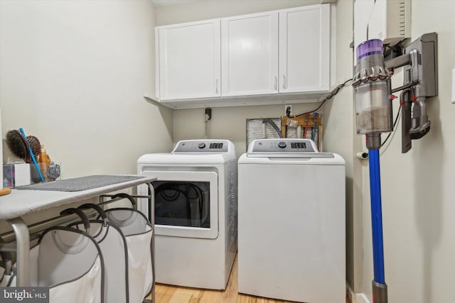 washroom with cabinet space, light wood finished floors, and independent washer and dryer