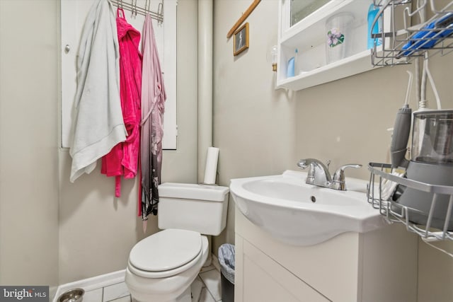 half bath with baseboards, vanity, and toilet