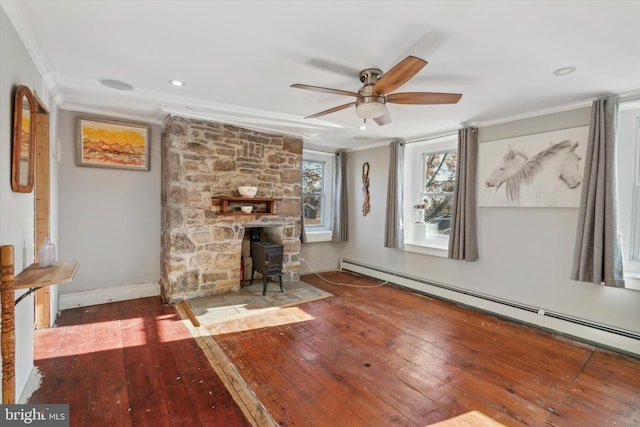 unfurnished living room with crown molding, a baseboard radiator, wood-type flooring, a ceiling fan, and a wood stove