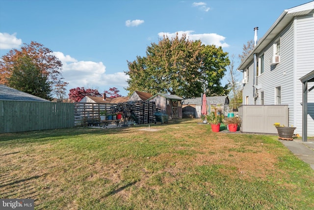 view of yard with a storage shed, a fenced backyard, and an outbuilding