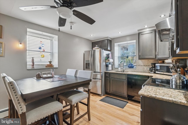 kitchen with stainless steel appliances, a sink, ventilation hood, light wood-type flooring, and tasteful backsplash