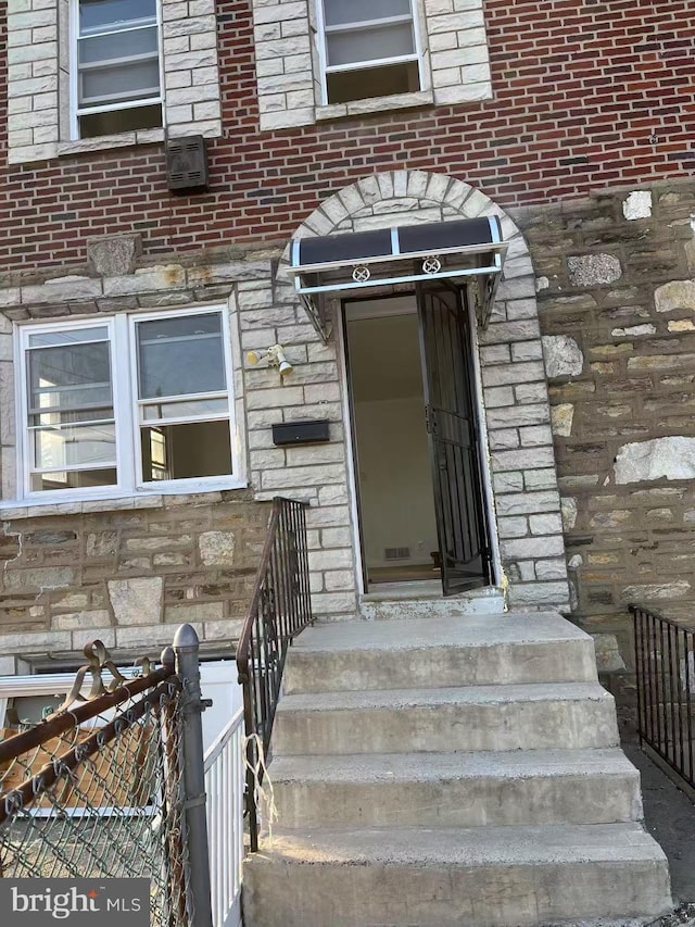 property entrance featuring stone siding and brick siding