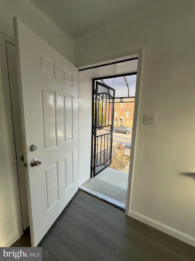 doorway featuring dark wood finished floors and baseboards