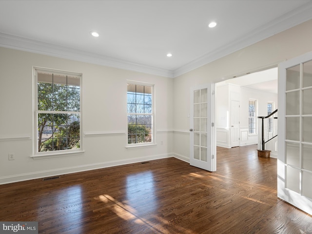 spare room with wood finished floors, visible vents, baseboards, stairway, and crown molding