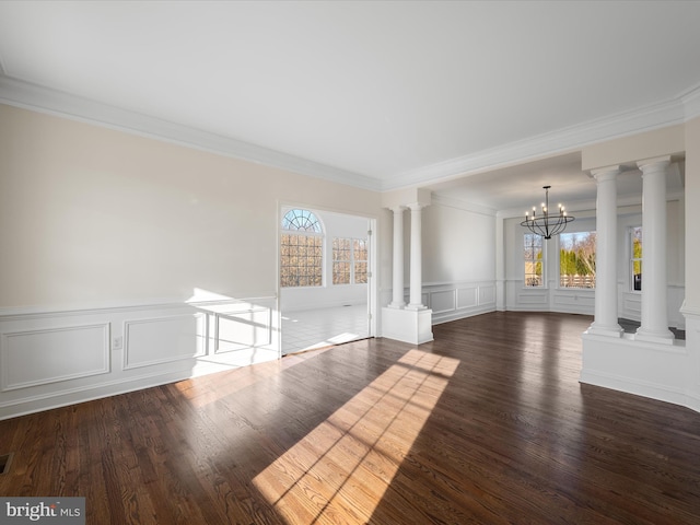 interior space featuring a notable chandelier, a decorative wall, wood finished floors, ornate columns, and crown molding