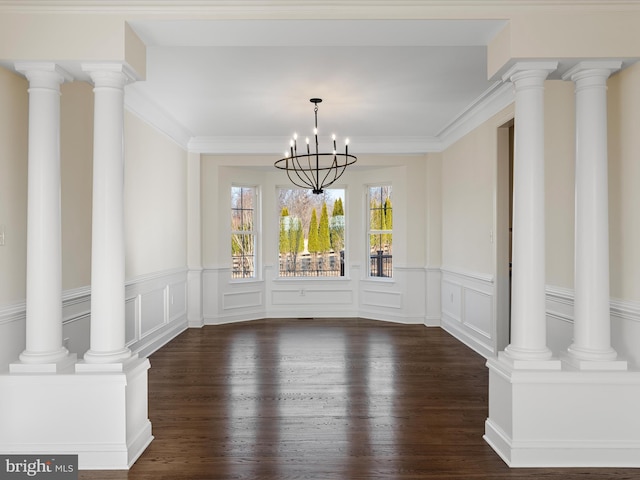 unfurnished dining area featuring dark wood finished floors, ornate columns, and an inviting chandelier