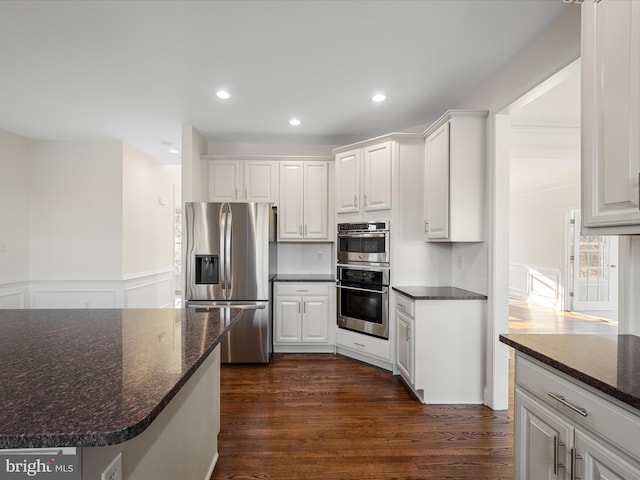 kitchen featuring white cabinets, stainless steel appliances, dark wood finished floors, and wainscoting