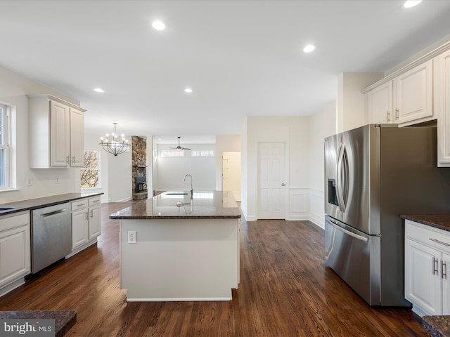 kitchen with dark wood finished floors, stainless steel appliances, recessed lighting, a kitchen island with sink, and a sink