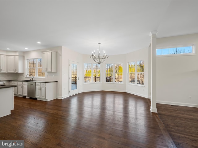 unfurnished living room with dark wood-style floors, decorative columns, recessed lighting, a sink, and baseboards