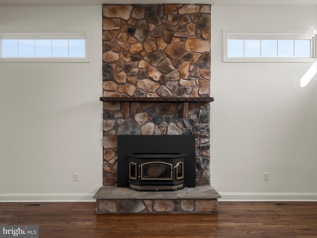 interior details featuring a wood stove, baseboards, and wood finished floors