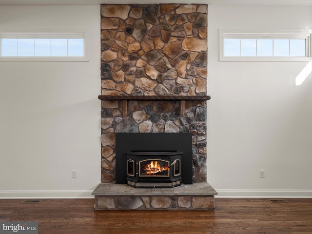 details featuring a wood stove, visible vents, baseboards, and wood finished floors