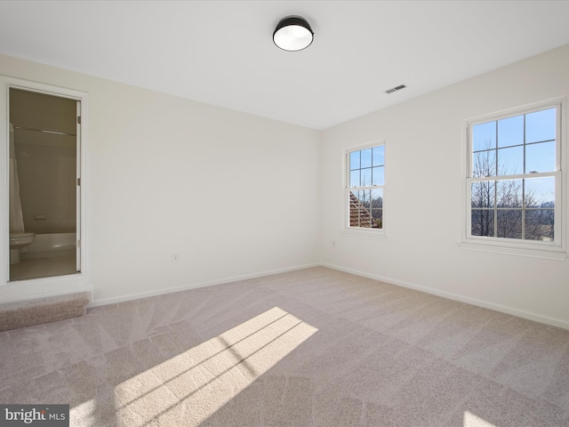 carpeted empty room with visible vents and baseboards