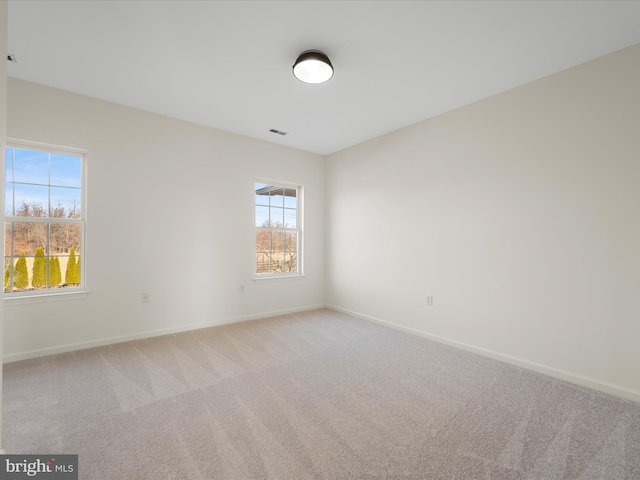 unfurnished room with carpet, visible vents, and baseboards