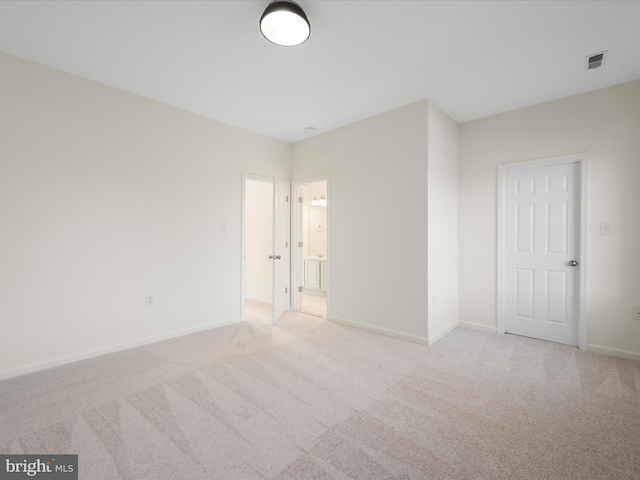 unfurnished bedroom with visible vents, ensuite bath, light carpet, and baseboards