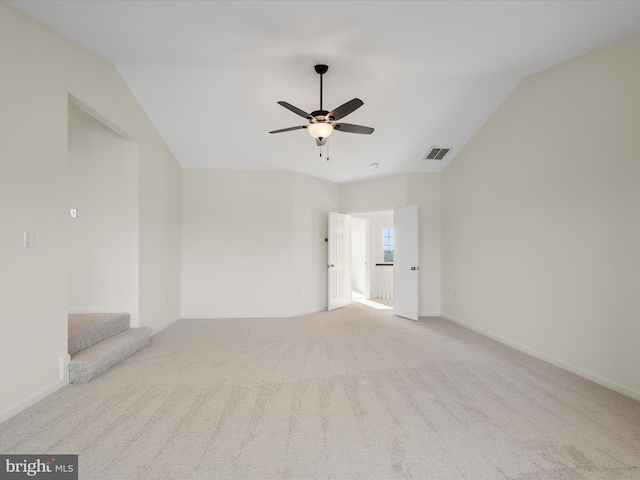 carpeted spare room featuring lofted ceiling, visible vents, a ceiling fan, and baseboards