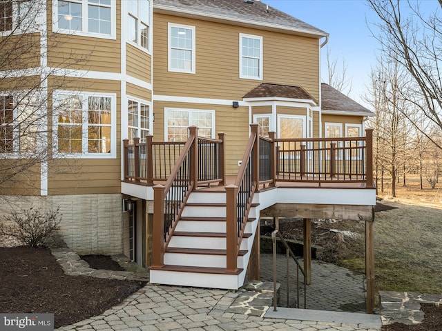 back of property with stairway, roof with shingles, and a deck