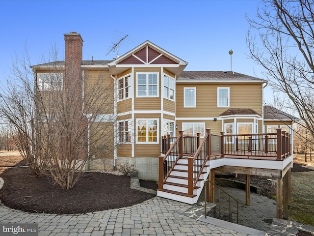 back of house featuring stairs, a chimney, and a wooden deck