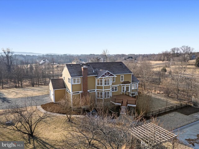 rear view of house with a chimney, fence, a deck, a garage, and driveway