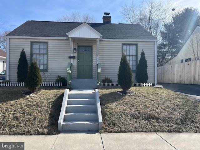 view of front of property featuring roof with shingles, a chimney, and fence