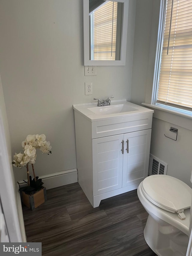 bathroom with visible vents, toilet, vanity, wood finished floors, and baseboards