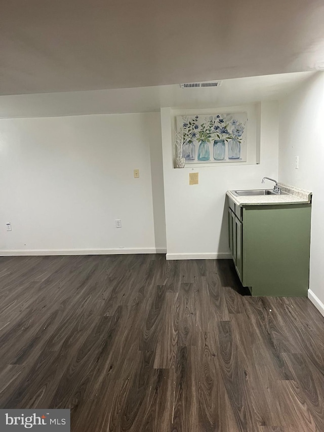 unfurnished room with dark wood-style floors, a sink, visible vents, and baseboards