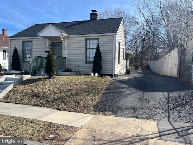 view of front of property with roof with shingles, a chimney, and fence