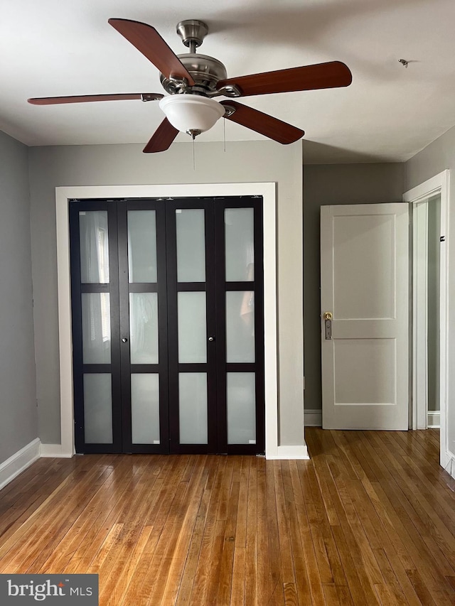 unfurnished bedroom featuring wood-type flooring, a ceiling fan, and baseboards