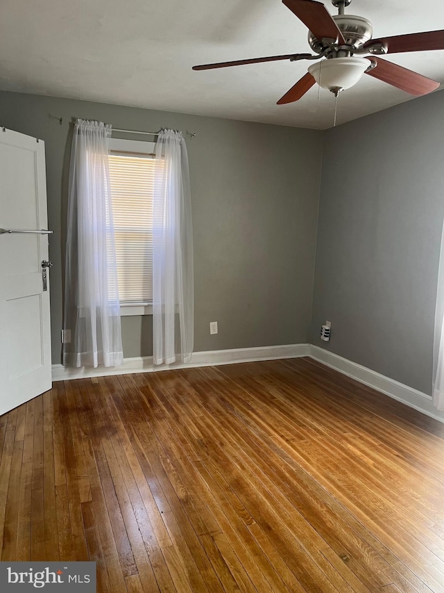 spare room with hardwood / wood-style flooring, baseboards, and a ceiling fan