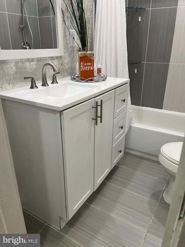 bathroom with toilet, tile patterned flooring, shower / bath combo with shower curtain, and vanity