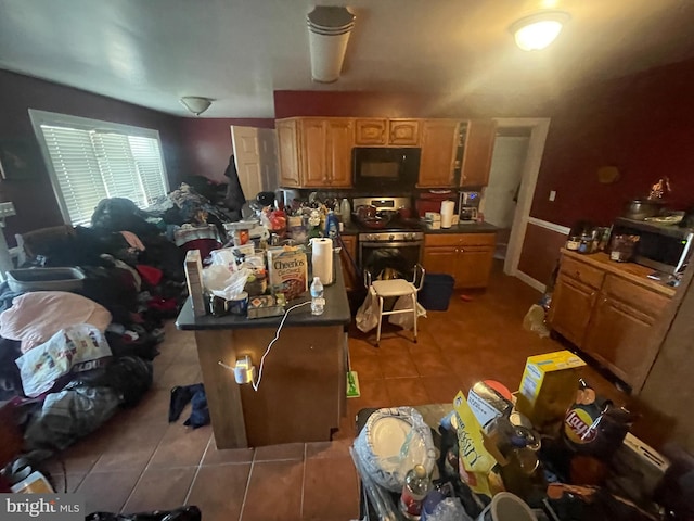 kitchen with dark countertops, stainless steel range with gas cooktop, black microwave, and tile patterned floors