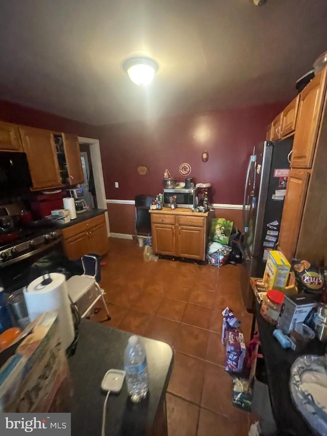 kitchen with brown cabinetry, tile patterned flooring, and freestanding refrigerator