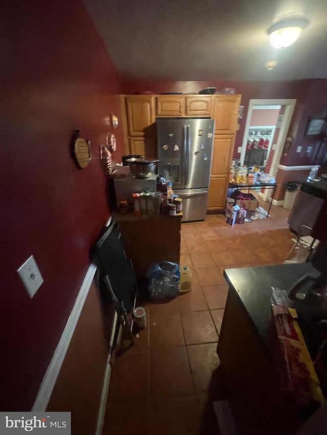 kitchen featuring light brown cabinetry, stainless steel fridge, baseboards, and light tile patterned floors