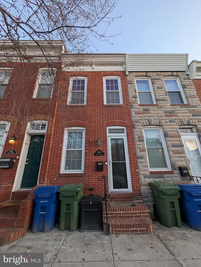 townhome / multi-family property featuring entry steps, stone siding, and brick siding