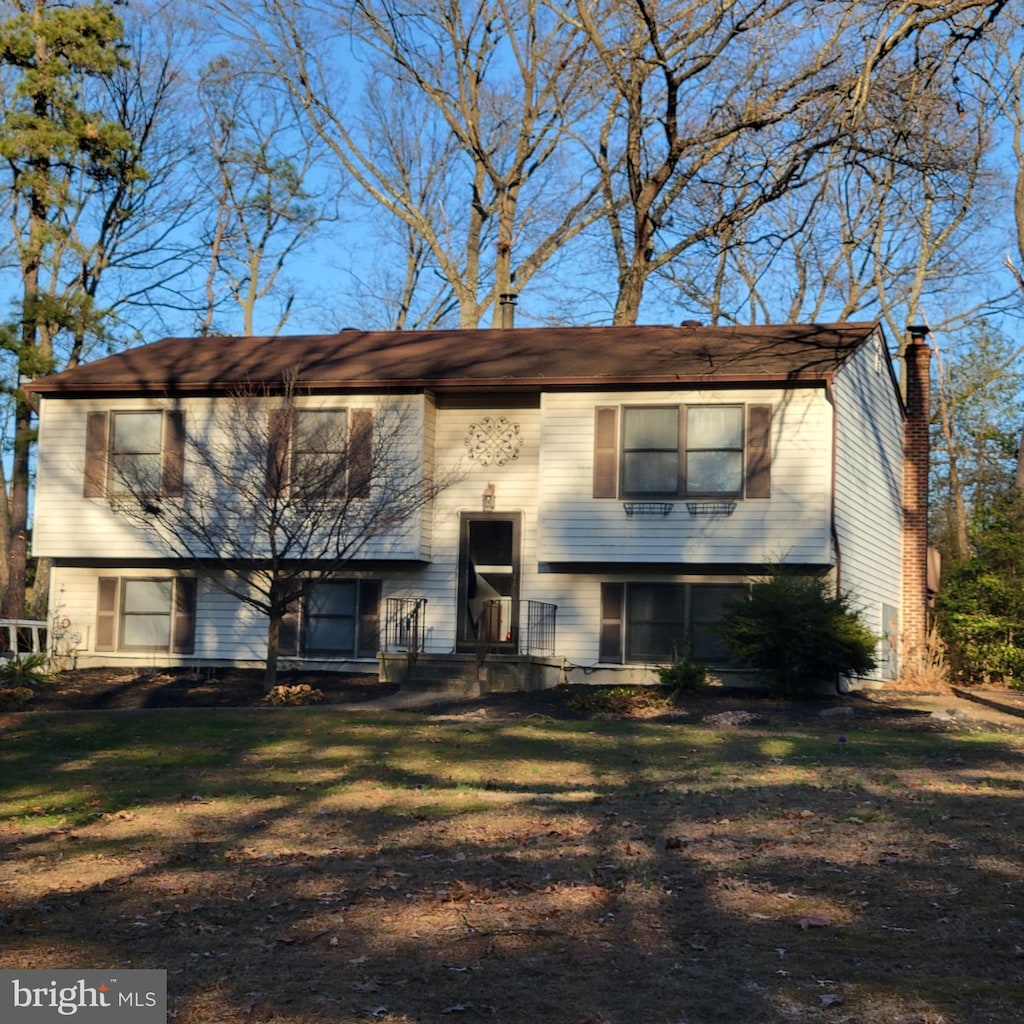 split foyer home featuring a front yard and a chimney