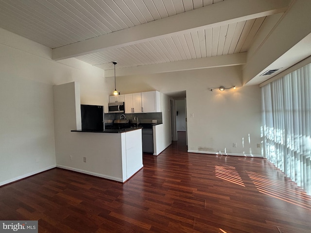 kitchen with refrigerator, dark wood finished floors, dark countertops, stainless steel microwave, and a peninsula