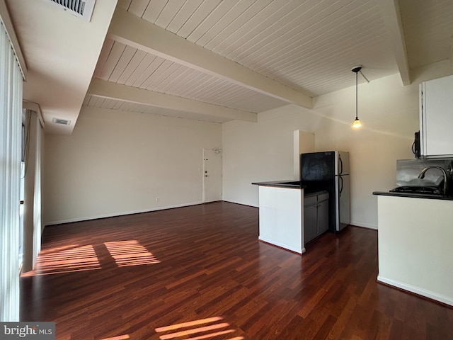 kitchen with visible vents, dark wood finished floors, dark countertops, beamed ceiling, and freestanding refrigerator