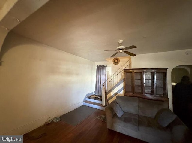 living area featuring dark wood-style floors, stairs, a ceiling fan, and baseboards