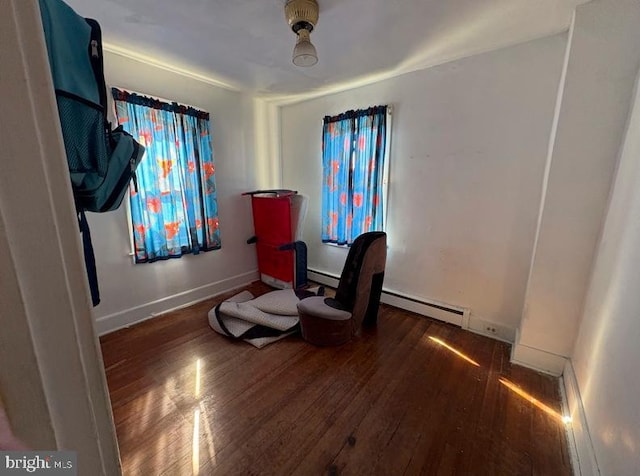 living area featuring a baseboard heating unit, baseboards, and hardwood / wood-style flooring