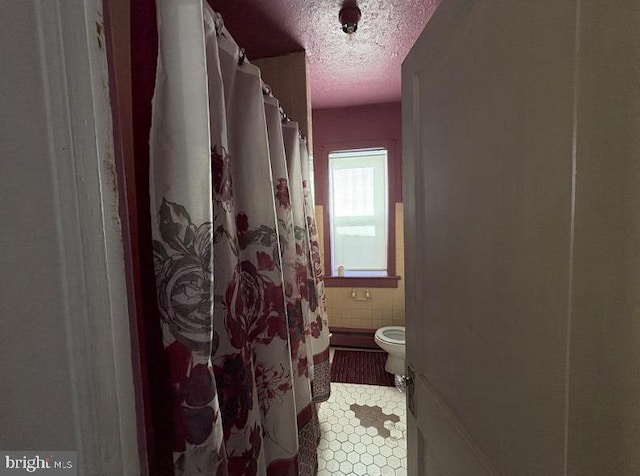 bathroom featuring tile patterned flooring, curtained shower, a textured ceiling, and toilet