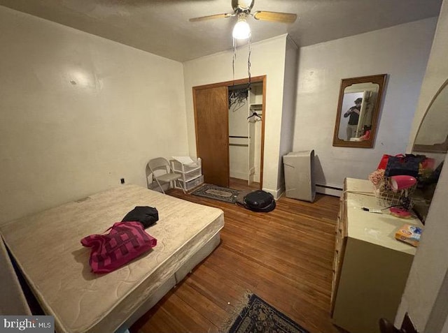 bedroom featuring a baseboard heating unit, ceiling fan, and wood finished floors