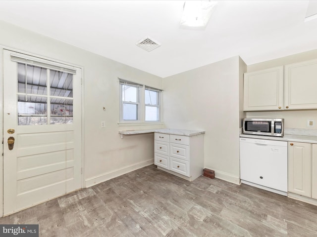 kitchen featuring visible vents, dishwasher, stainless steel microwave, light countertops, and light wood-type flooring