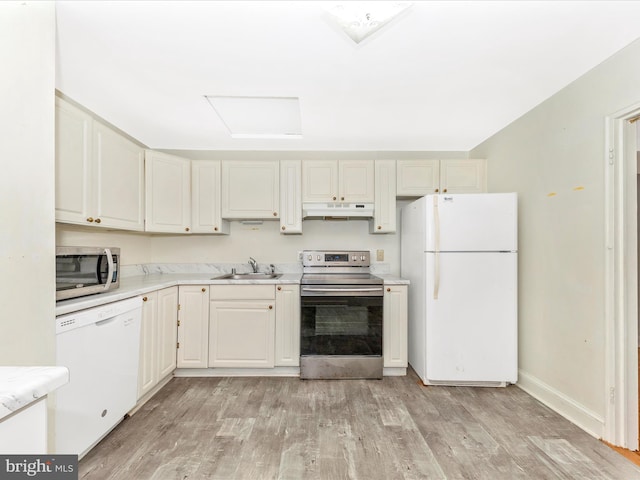 kitchen featuring light wood-style flooring, stainless steel appliances, light countertops, under cabinet range hood, and a sink