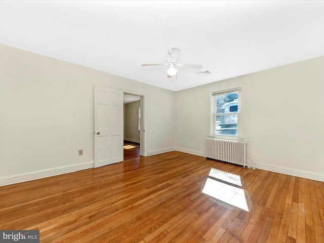 spare room with ceiling fan, light wood finished floors, radiator heating unit, and baseboards