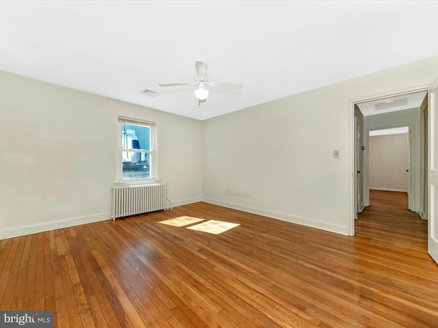 empty room featuring radiator, visible vents, ceiling fan, light wood-type flooring, and baseboards