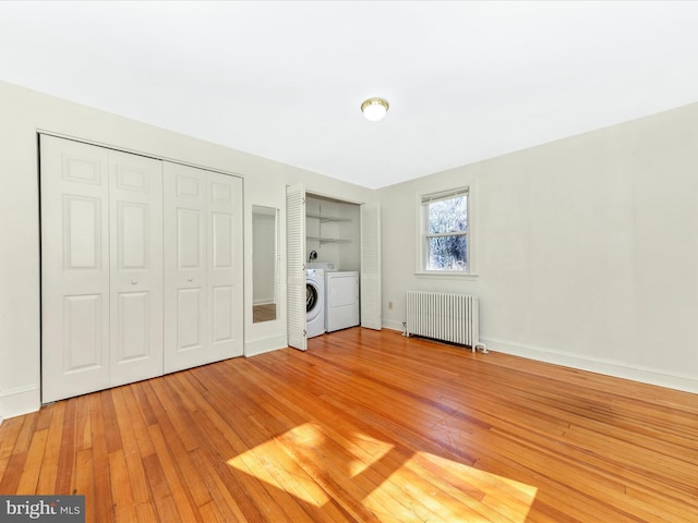 unfurnished bedroom with light wood finished floors, radiator heating unit, two closets, and baseboards